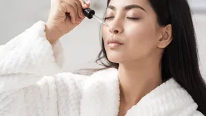 Young asian woman applying serum on facial skin