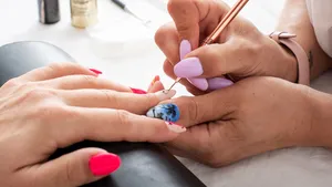 Woman getting her nails done in salon by manicure worker