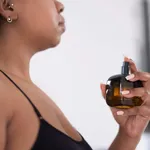 Close-up of woman spraying perfume on neck