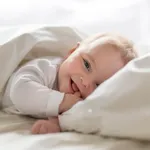 Cute happy 7 month baby girl in diaper lying and playing