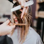Beautiful young woman getting her haircut by a hairstylist at a beauty salon.