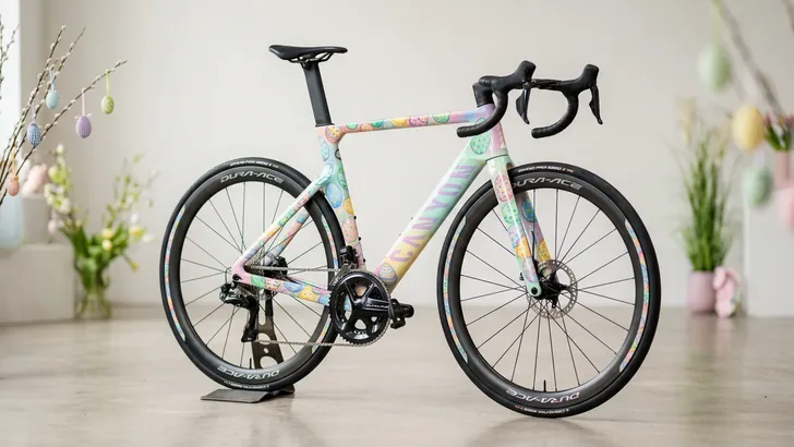 Close-up van een high-end Canyon Aeroad racefiets met een custom paasei-patroon op het frame, gefotografeerd in een professionele studio-omgeving.