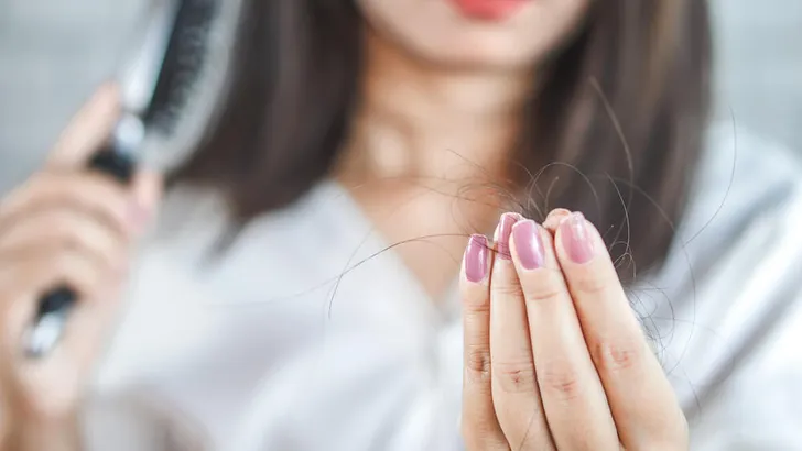 woman hand holding hair fall from hairbrush
