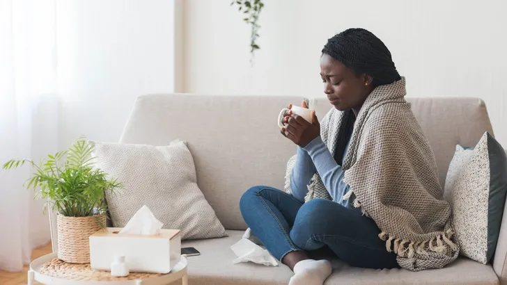 Sick Black Girl Drinking Hot Tea On Sofa At Home