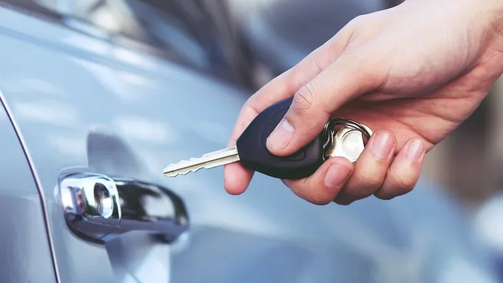 Cropped view of  Closeup of a man's hand inserting key into the door lock of a car