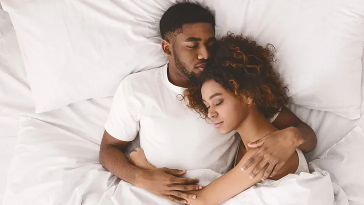 Young black couple sleeping together in bed