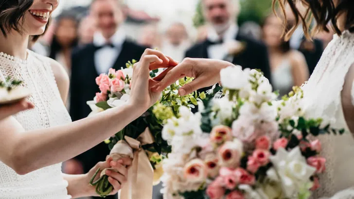 CU two LGBT females lesbians brides exchanging rings during wedding ceremony