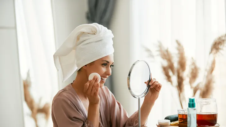 Vrouw met skincare bij spiegel. – 63% van vrouwen heeft eigen huidtype fout