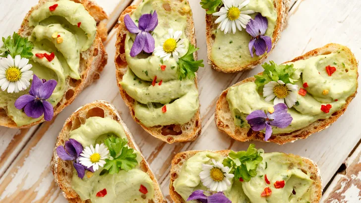 Delicious canapes with avocado paste and edible flowers vegan