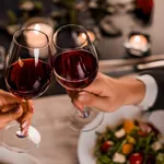 Close up of young couple toasting with glasses of red wine at restaurant