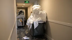 Schoonmaakkar vol vuile witte lakens van hotelgasten.