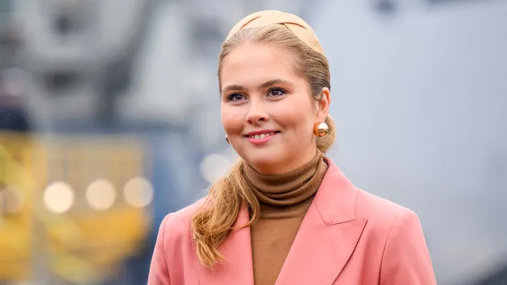 Amalia lachend in roze jas en beige trui met haarband in haar