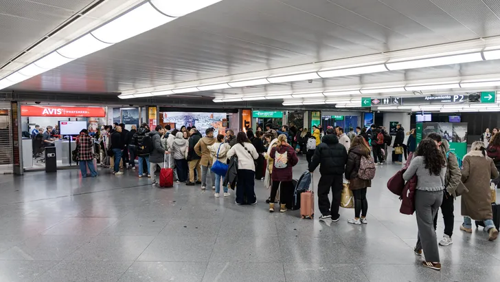Reizigers wachten met bagage bij autoverhuurbalies op een luchthaven