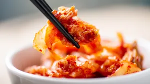 Hand die eetstokjes vasthoudt om kimchi te eten, Koreaans gerecht