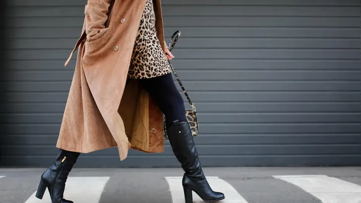 Stylish woman in black shoes walking across the street