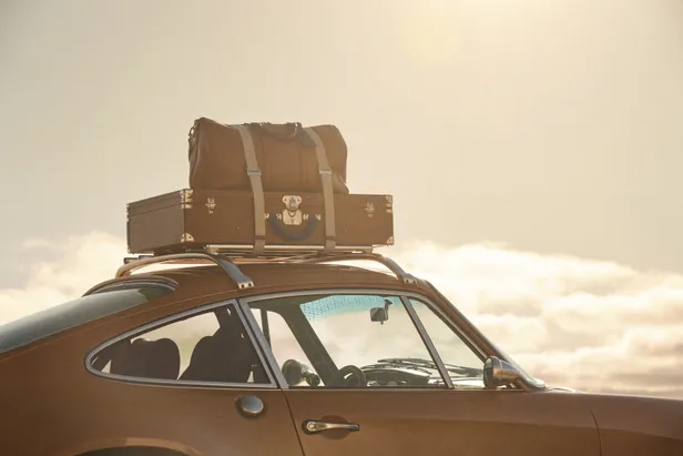 Louis Vuitton-koffers vastgebonden op het dakrek van de saffraankleurige Singer Porsche 911.