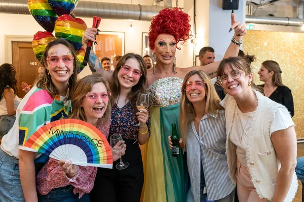 Groep lachende mensen bij een Pride-feestje bij Mindspace Dam in Amsterdam. 