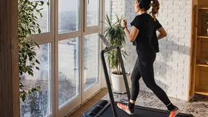 Woman jogging on the modern compact treadmill at home