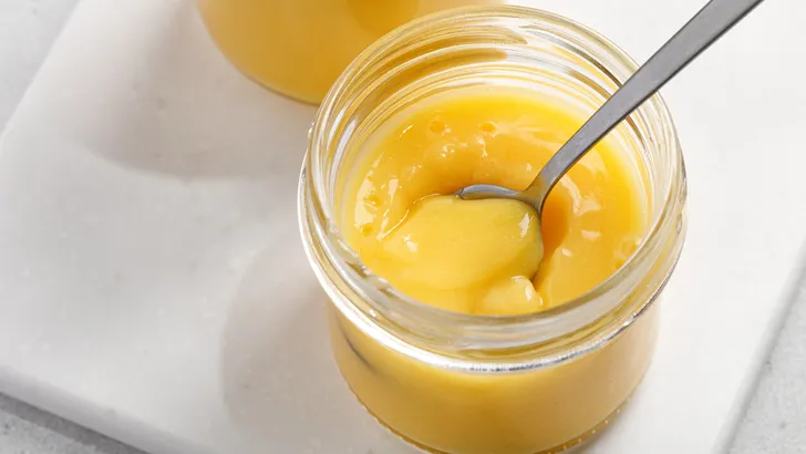 Delicious homemade lemon curd decorated with fresh fruit in a glass jars. Lemon dessert.