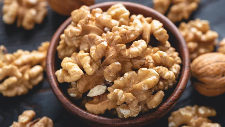 Gepelde walnoten in een kom op een zwarte stenen achtergrond, close-up. Gezonde noten als tussendoortje.