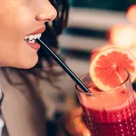 A middle-aged woman  sitting in a cafe and enjoying in a fresh beetroot and grapefruit juice.