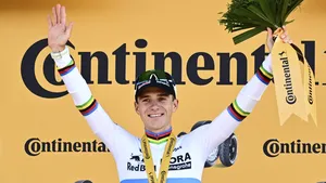 Remco Evenepoel op een gouden tijdritfiets in de regenboogtrui bezig aan een tijdrit langs het Meer van Genève