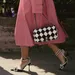 6 tips om de perfecte hakken te kopen. – Foto van vrouw in roze trenchcoat met Chanel-tas op zwart-witte stiletto-hakken.