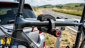 Close-up van de klemarm van een fietsendrager die direct en zonder bescherming is vastgeklemd op de carbon bovenbuis van een racefiets.