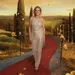 Yvonne van De Golden Bachelor in goudkleurige jurk op rode loper met Toscane op achtergrond