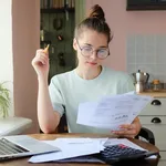 Indoor picture of young European female sitting at home at table