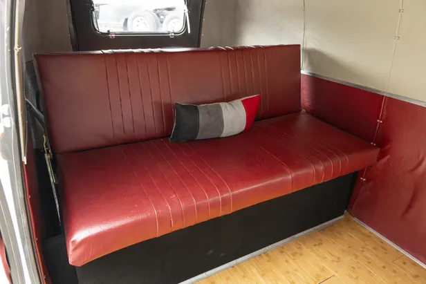 Rode neerklapbare achterbank met kussen in de laadruimte van de Volkswagen-bus.