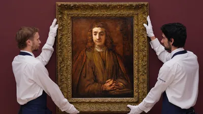 Twee mannen in wit pak met een schilderij van Rembrandt van Rijn
