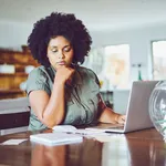 Woman looking concerned while paying bills from home