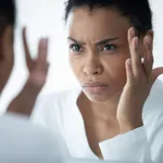 African woman looking in mirror see mimic wrinkles feels stressed