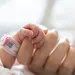 Foto van babyhandje dat vinger vasthoudt van moeder. – Raarste naam ooit? Deze kindernaam staat bovenaan de lijst