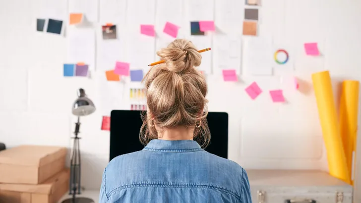 Rear View Of Businesswoman With Hair Held Up With Pencil Working On Computer