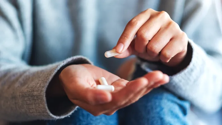 Een vrouw houdt supplementen in haar hand.