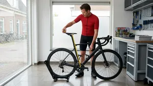 Mannelijke wielrenner staat in fietskleding naast zijn racefiets en stelt zonder helm zijn zadelhoogte af met gereedschap.