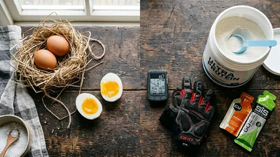 Een flat lay van fietshandschoenen, een GPS en een mix van eieren en sportsupplementen.
