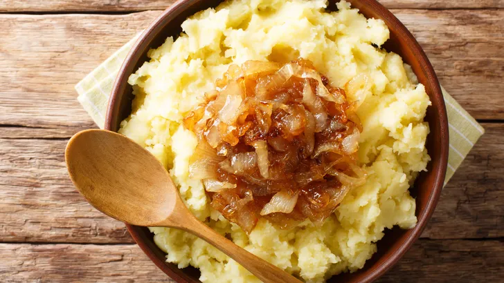 Vegetarian rustic food mashed potatoes with caramelized onions close-up on a plate on the table. Horizontal top view