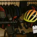 Overvoll racefiets-stuur met GPS, lampjes en extra gadgets, met op de achtergrond een rek vol wielershirts en een helm met prijskaartje €299,95.