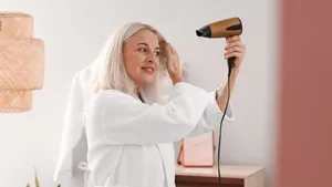 Vrouw van zestig plus vrouw die haar haar föhnt.