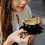 Young asian woman holding a cup of coffee with saucer