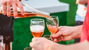 the pouring of fruit cider into two glasses in the hands