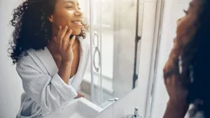 Pleased lady in a bathrobe staring at her reflection