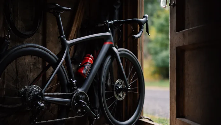 Dure racefiets in een garage met deur op een kier, vastgemaakt met een kettingslot