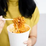 woman hand holding cup of spicy noodles, a woman eating noodle