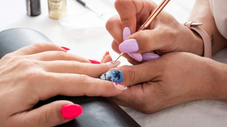 Woman getting her nails done in salon by manicure worker