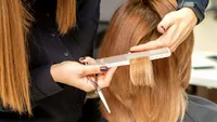 Hairdresser cuts hair to young woman