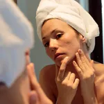 young woman looking her acne scars on the mirror